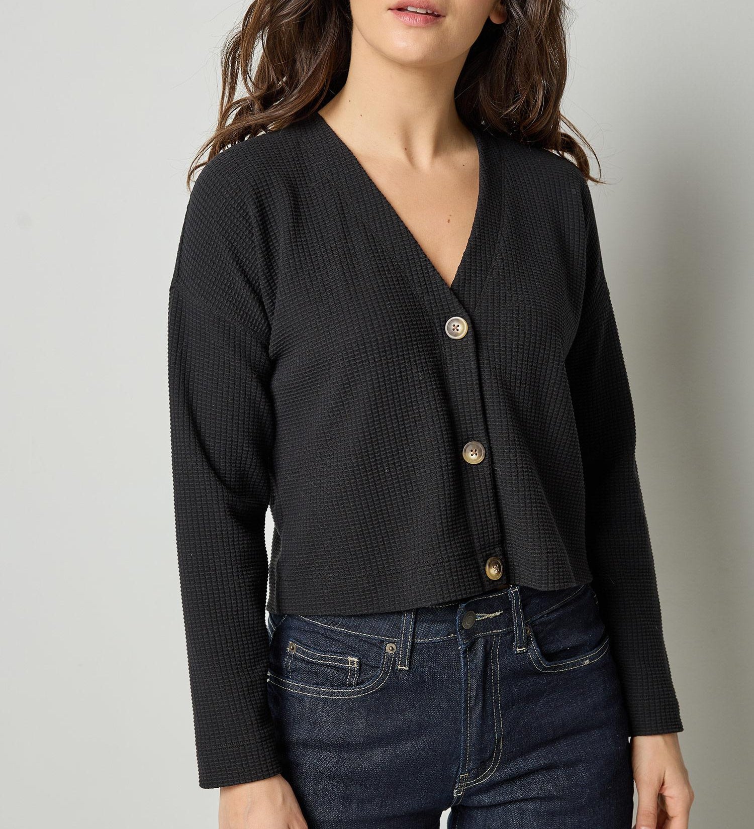 Black cotton waffle knit cardigan with long sleeves and cropped fit by Lilla P, front view.