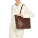 Model carrying the Il Bisonte Nina tote bag in coffee styled with elevated everyday and travel essentials